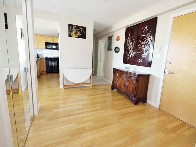 The entrance hall, hardwood running back past a mirrored wall to the kitchen.