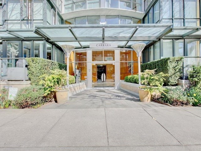 The entrance, a glass canopy over the doors with planting either side.