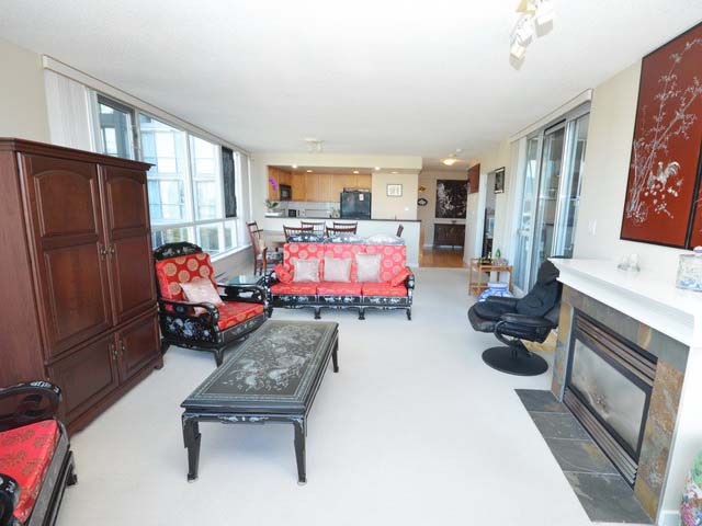 The living room, a gas fireplace set in the wall with the windows turning the corner beside it.