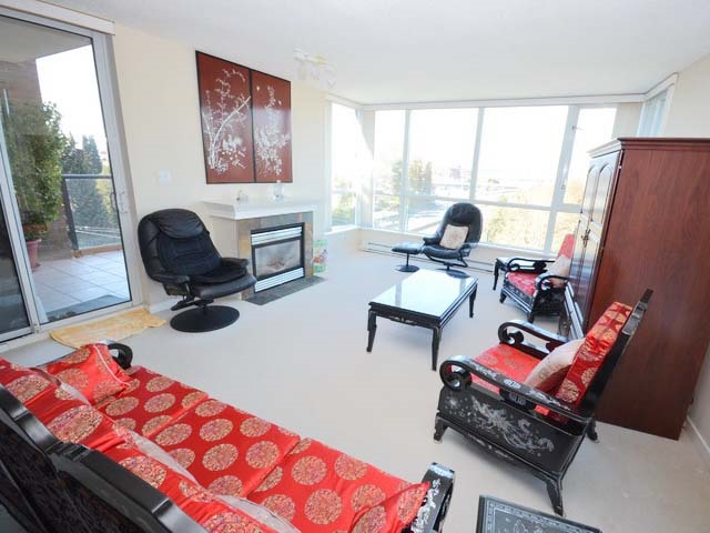 The living room from the far end, windows on two sides and the balcony door between them.