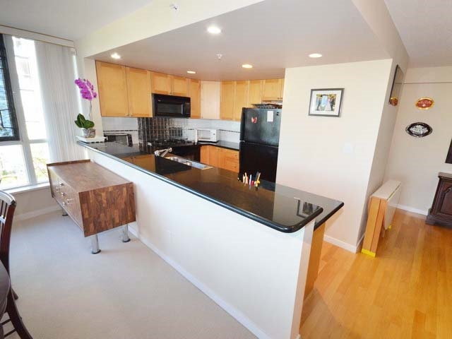 The kitchen from the dining room, a granite peninsula with the counter running back to the windows.
