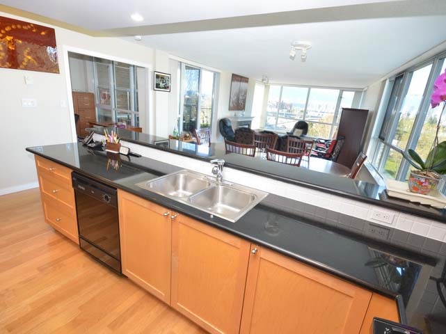 The kitchen along its length, maple cabinets and dark granite, open to the living room at the far end.